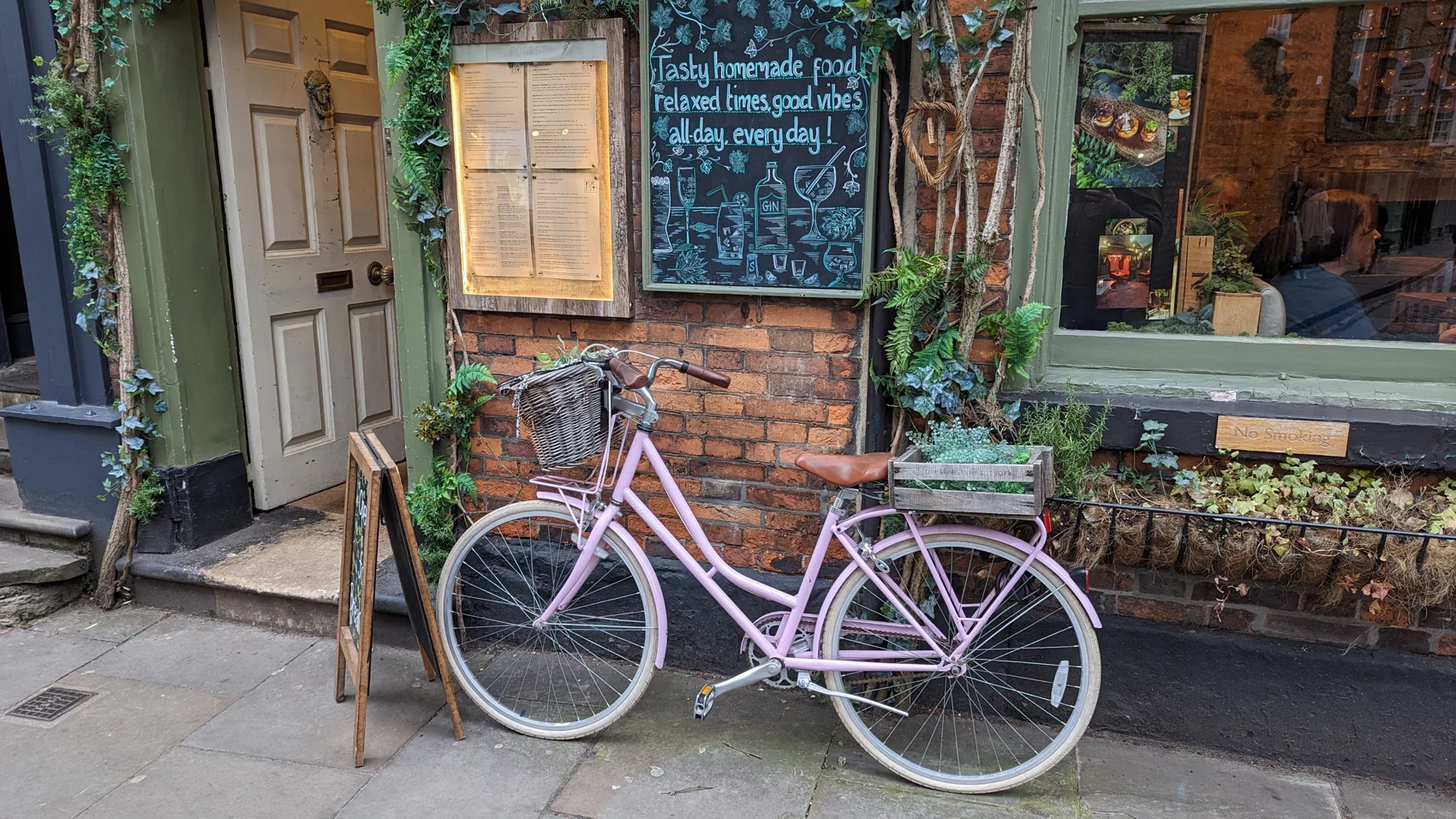 A bicycle outside a cafe with handwritten window signs.